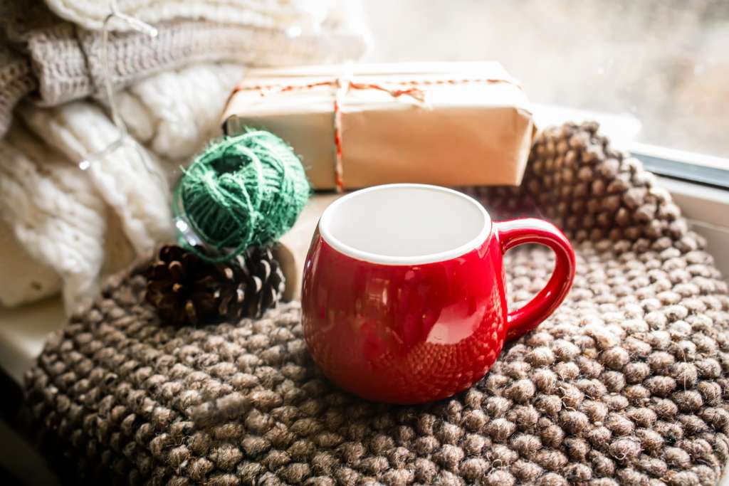 An empty red Christmas cup on a cozy blanket