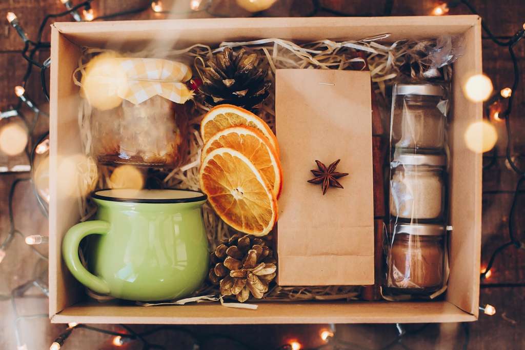 Gift box with tea set. Tea, cup, jam, spices, dried oranges in box with christmas lights, top view