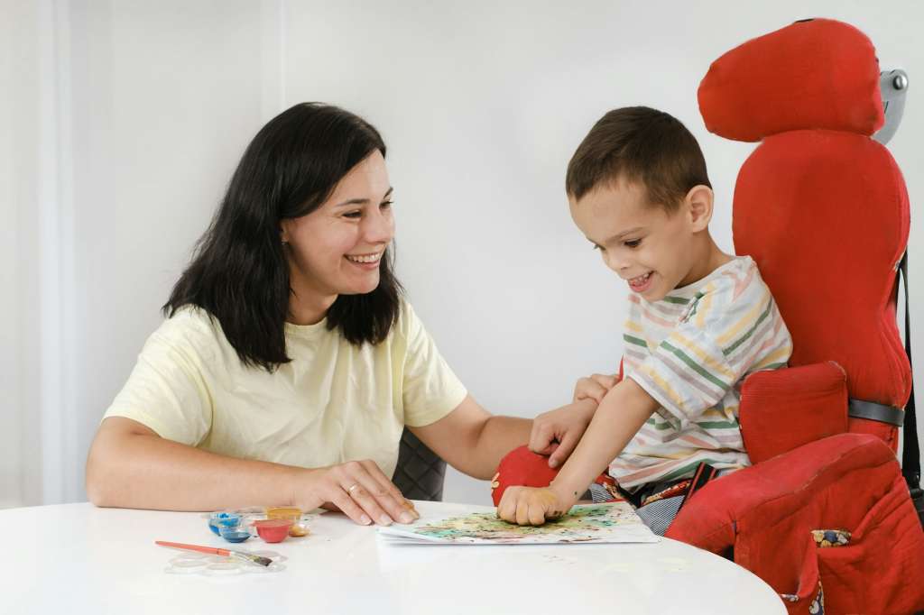 Child with cerebral palsy painting, mental physical disorders sensory therapy