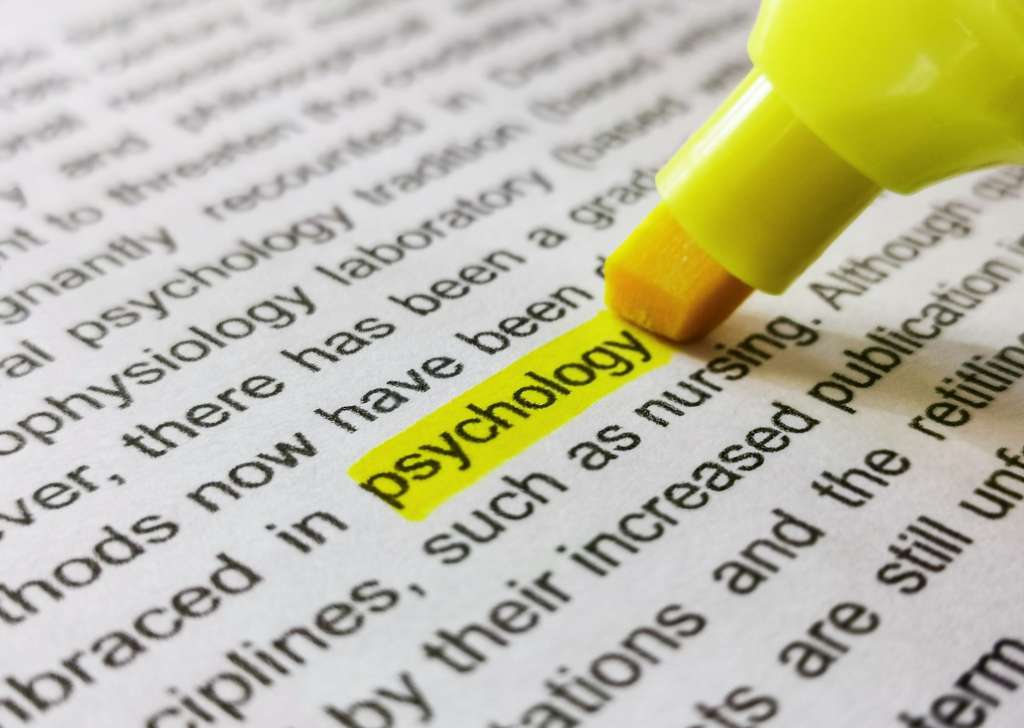 Close-up image of marker highlighting word psychology in book.